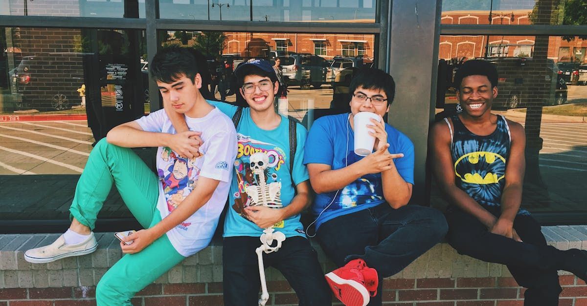 A group of young men are sitting on a brick wall.