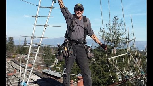 A man is standing on top of a roof with his arms in the air.