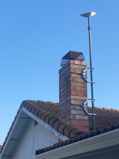 A brick chimney is sitting on top of a tiled roof.