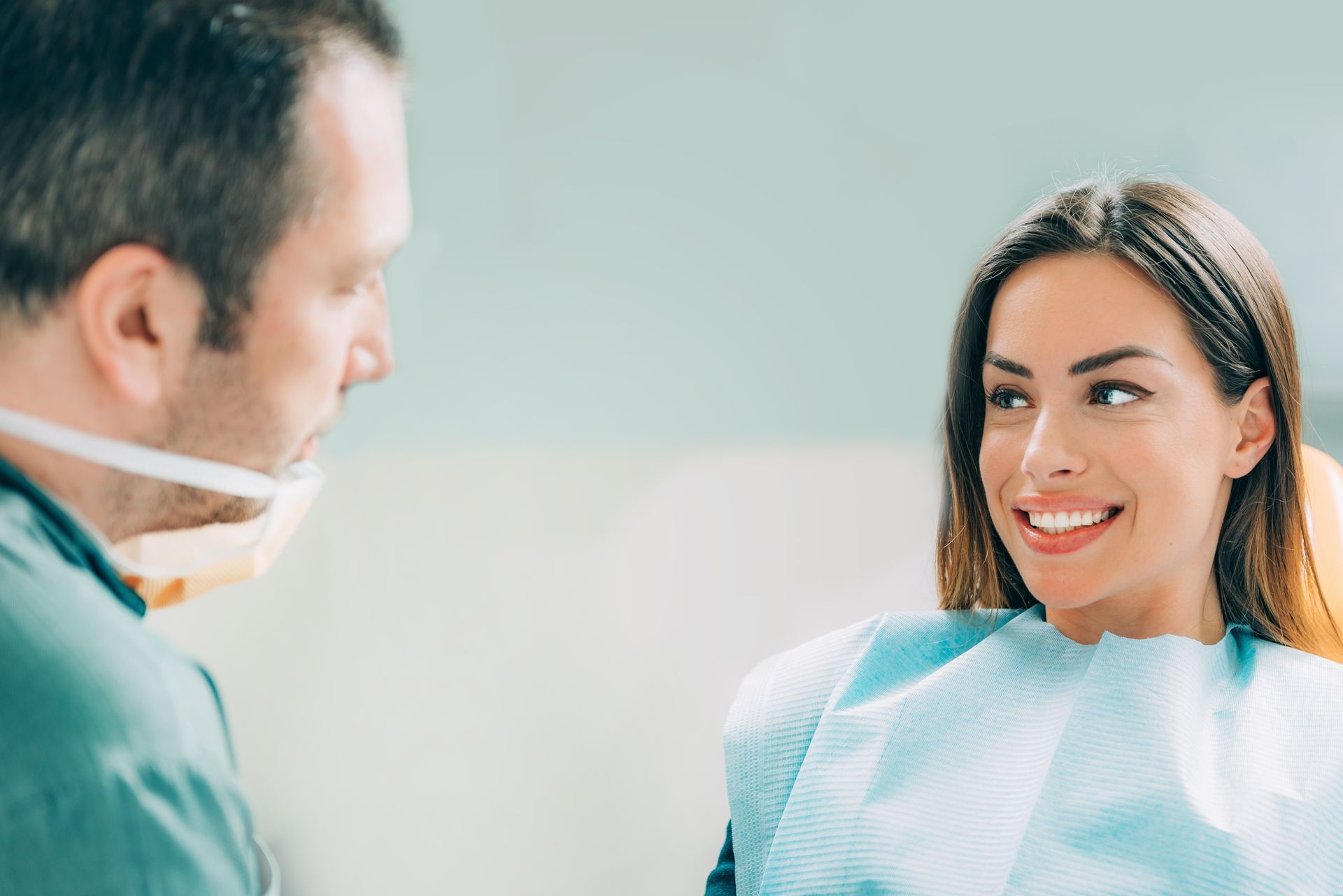 A happy patient smiling during a consultation with an expert cosmetic dentist in a modern office. A happy patient smiling during a consultation with an expert cosmetic dentist in a modern office.