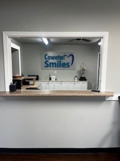 A woman in a dentist chair smiles, looking at her teeth in a hand mirror. A woman in a dentist chair smiles, looking at her teeth in a hand mirror.