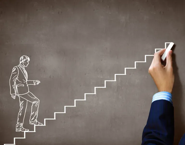 Hand drawing a staircase beside a chalk sketch of a person climbing upward on a gray wall