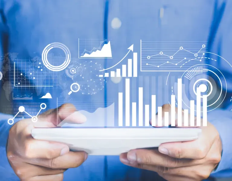 Hands holding a tablet with blue digital analytics charts and graphs overlayed on the screen