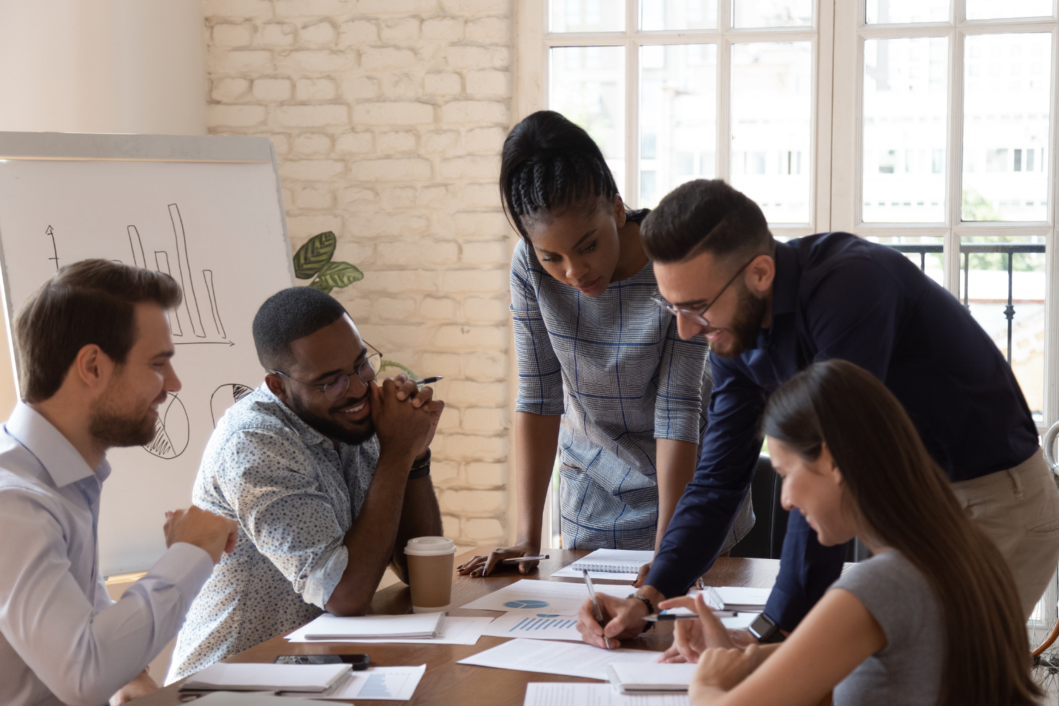 Team collaborating around a table in a bright office, reviewing documents and discussing ideas