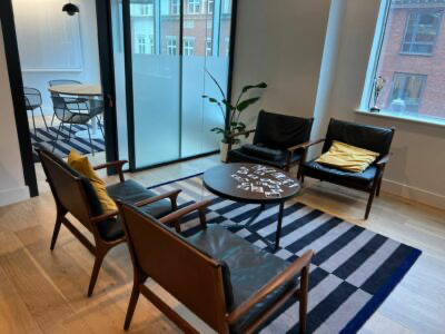 Modern living room seating area with striped rug, glass coffee table, and balcony doors with city view