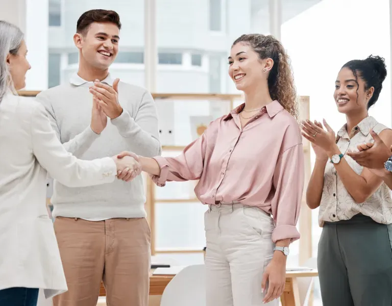 People shaking hands and applauding in a bright office setting
