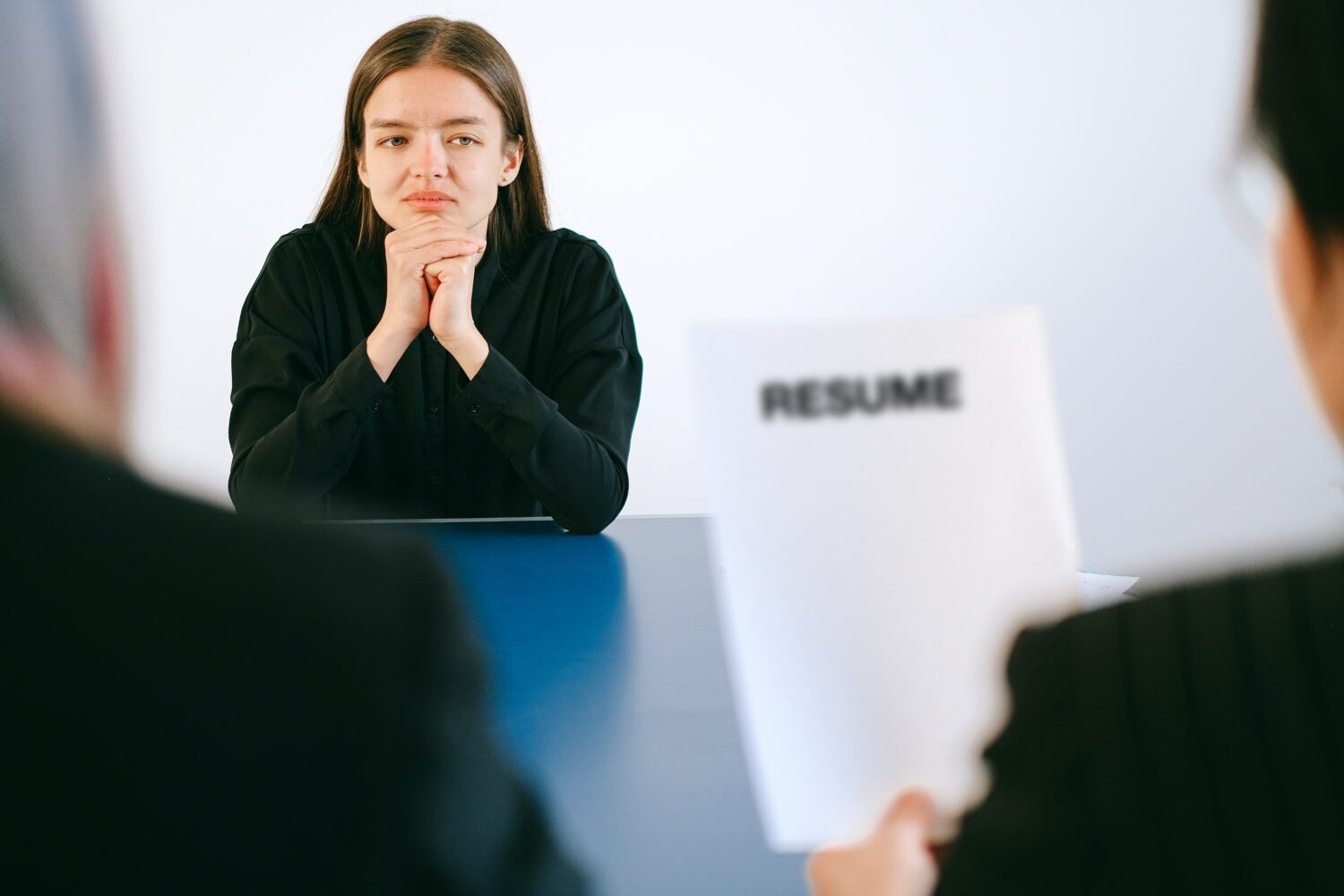 Job candidate seated at a table during an interview, with a resume in the foreground.