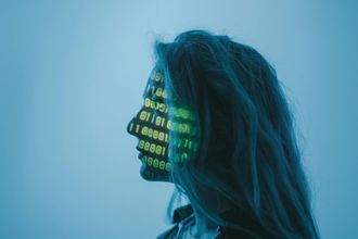 Side profile of a person with glowing green binary code projected on their face against a blue background