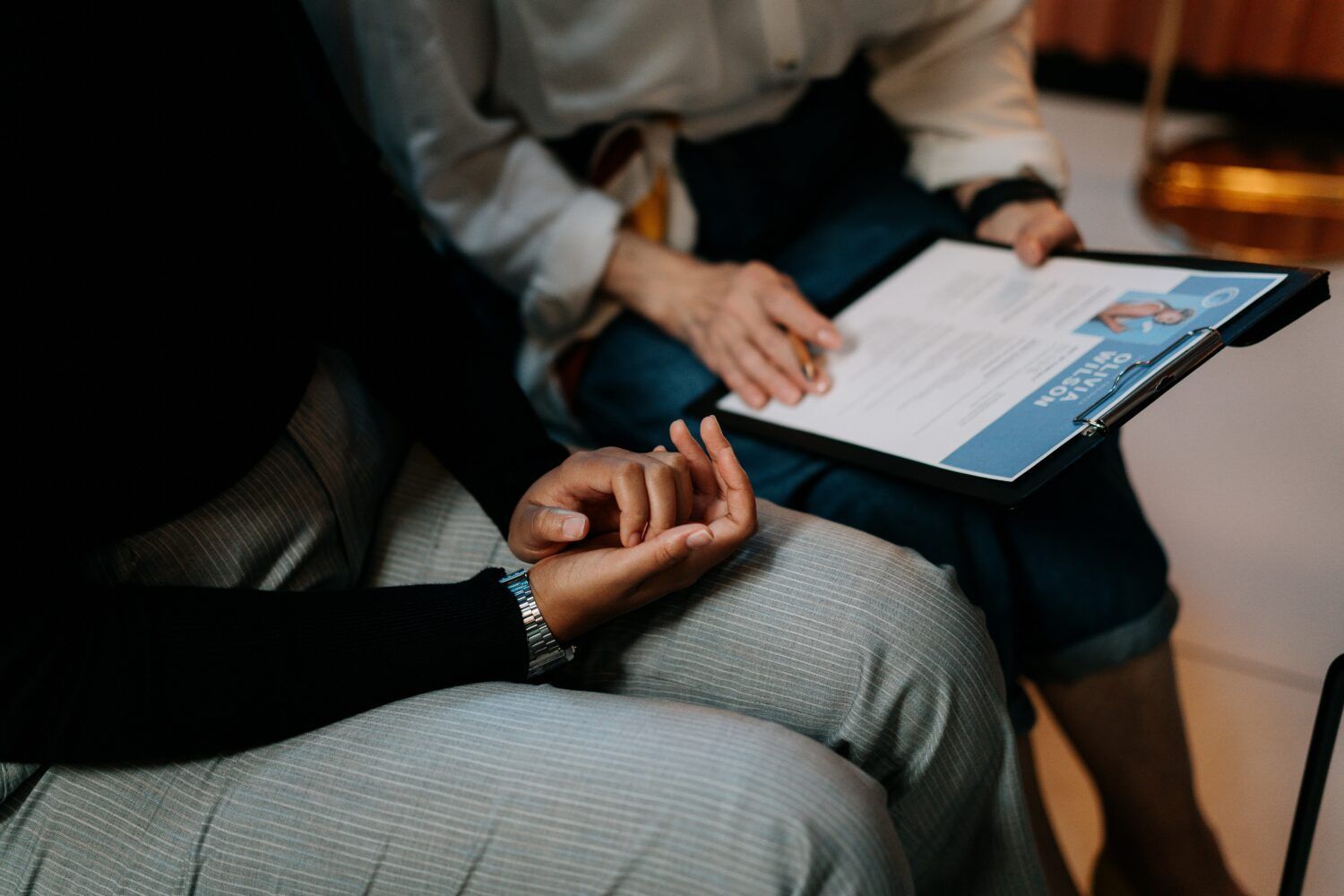 Two people reviewing paperwork on a clipboard in a meeting setting