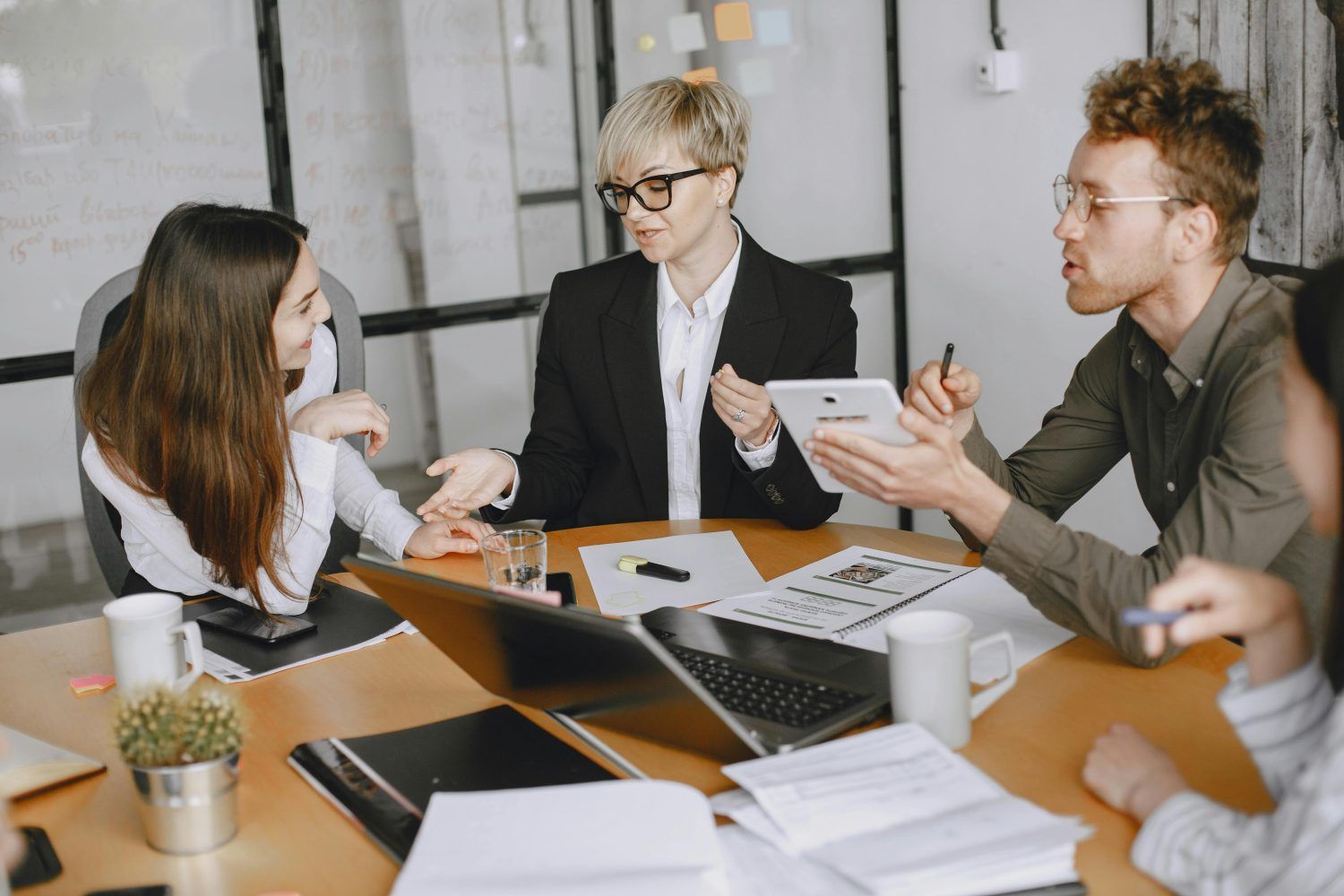 Three coworkers discussing documents around a laptop at a conference table