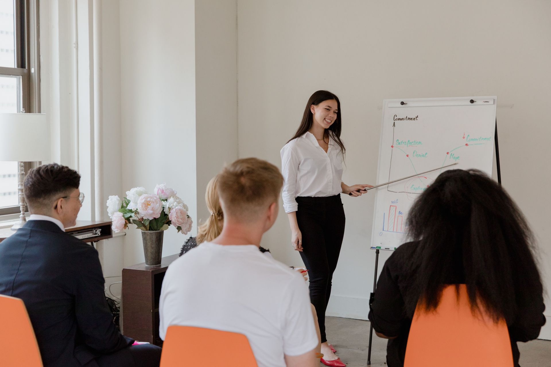 Presenter speaking to seated audience during a meeting beside a whiteboard