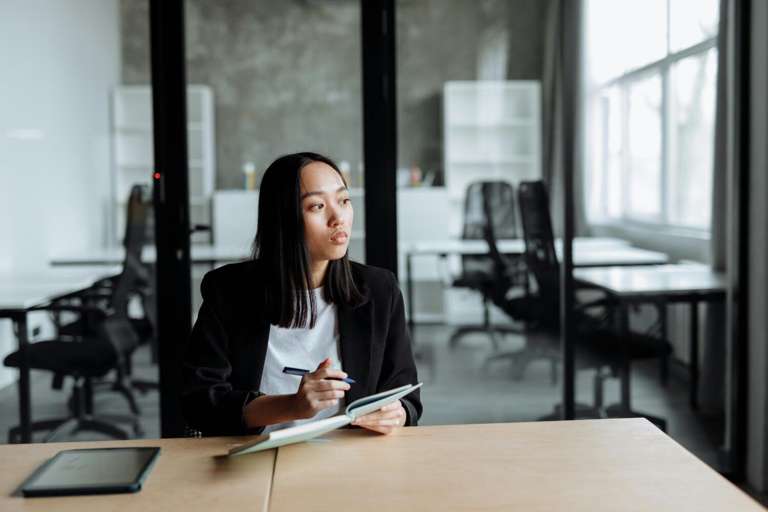 Person taking notes at a table in a modern office conference room