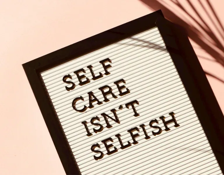Lightbox sign reading “SELF CARE ISN’T SELFISH” in black letters on a white background