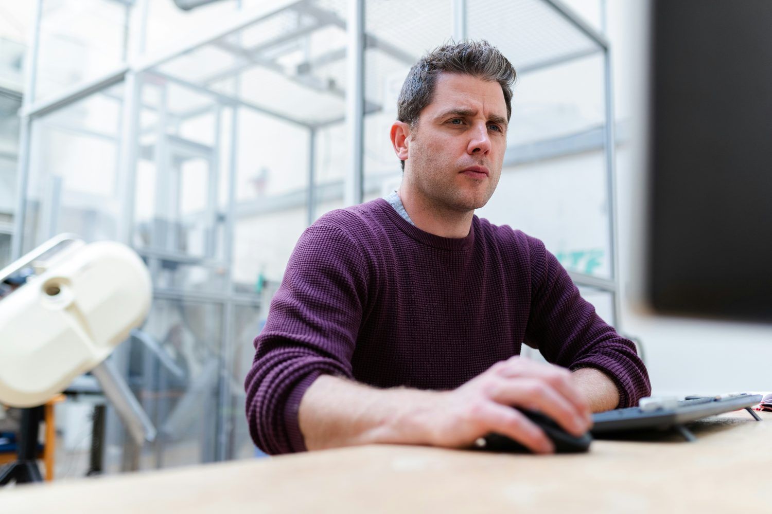 Man using a laptop at a desk in a bright lab or office setting