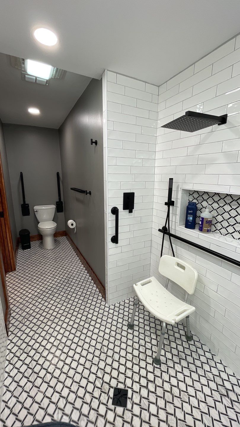 Bathroom with white tile floor, toilet, shower with bench seat, and black fixtures.