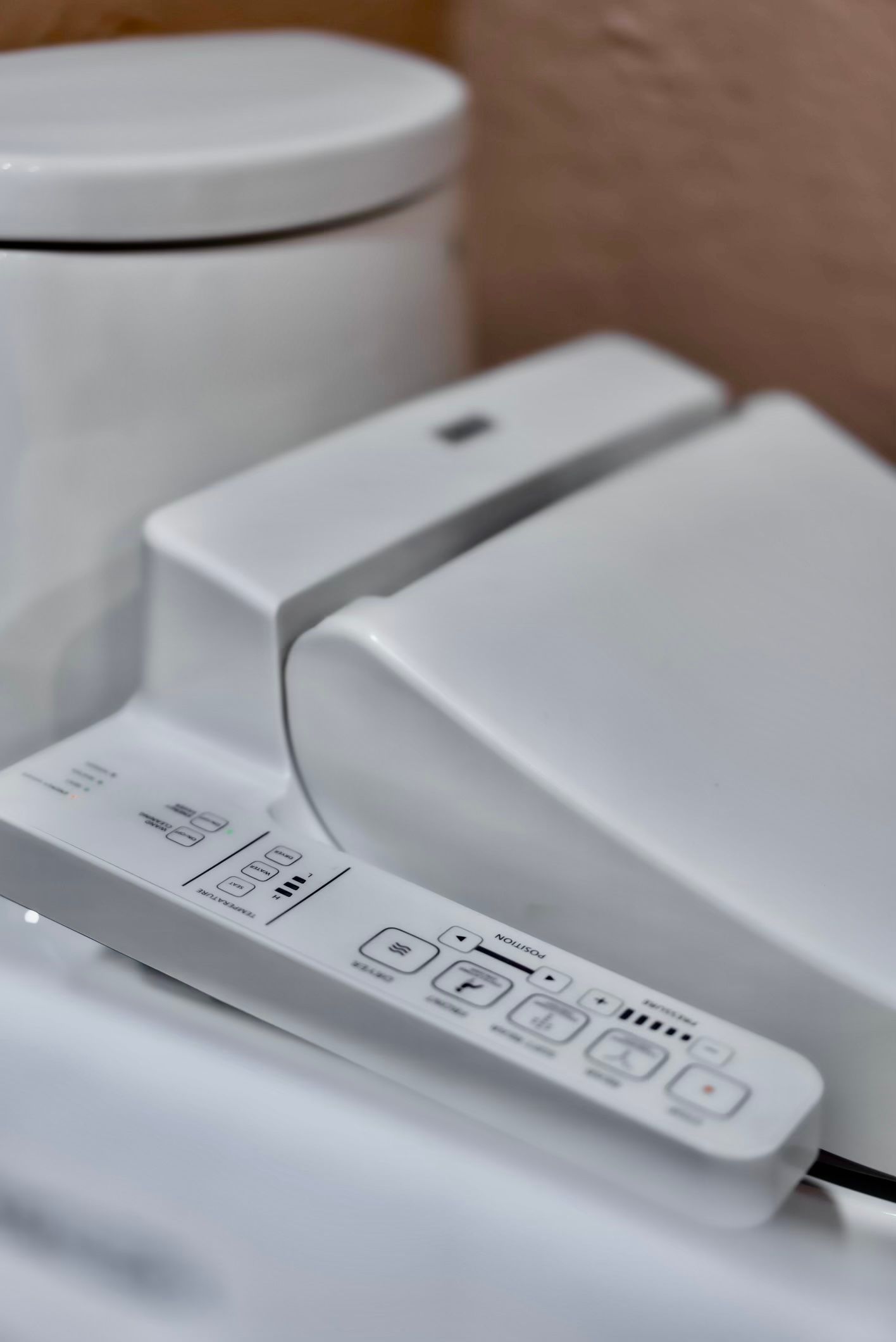 White bidet seat with control panel attached to a toilet.