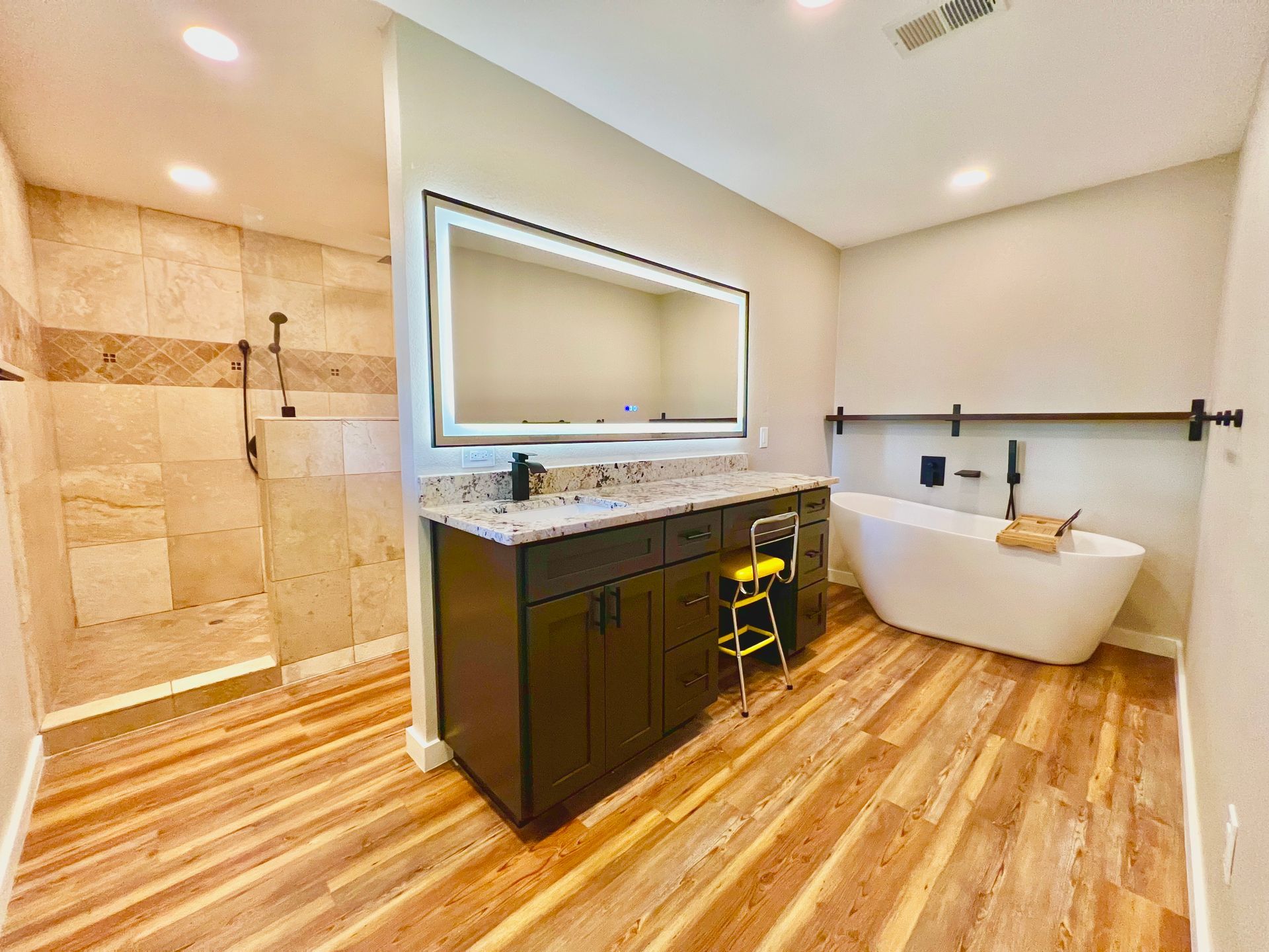 Bathroom with a walk-in shower, vanity with a lit mirror, and a standalone tub.