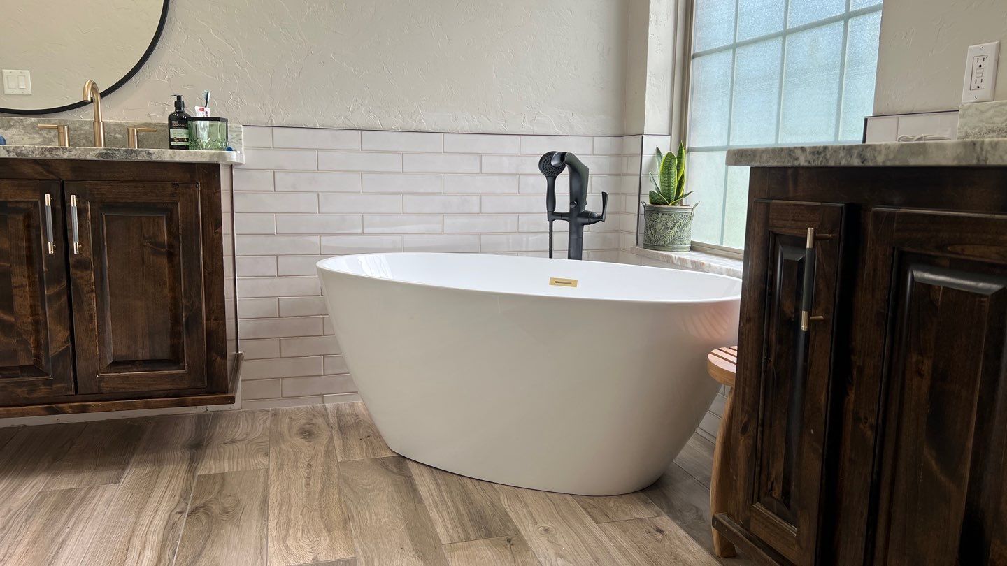 Bathroom with a white oval bathtub, dark wood cabinets, and a window.