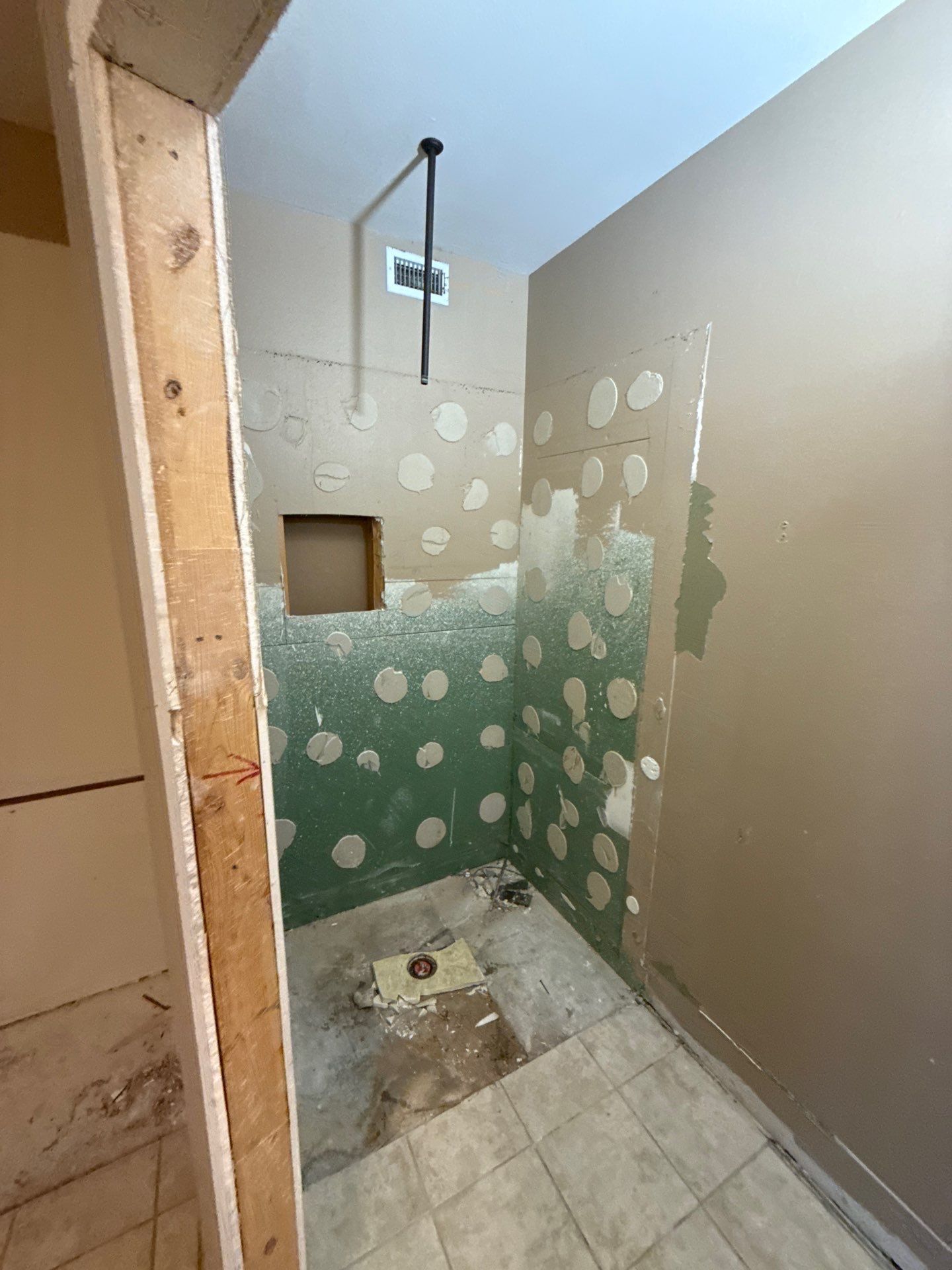 Bathroom under construction with green cement board and exposed studs.
