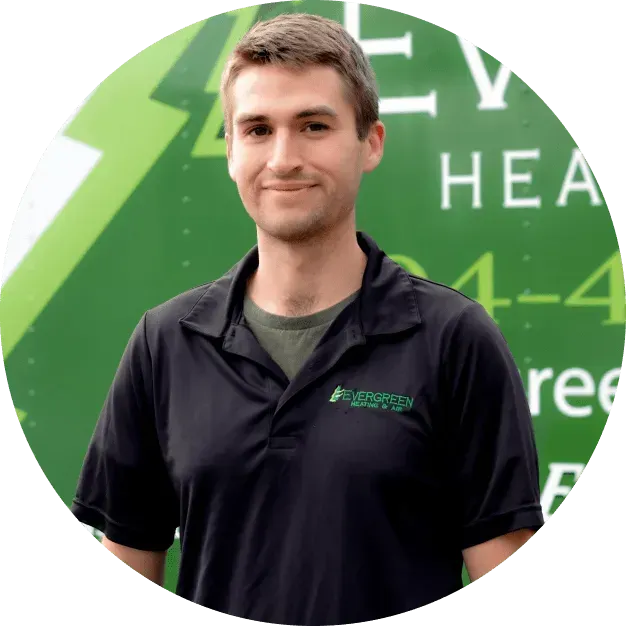 A person wearing a black polo shirt with an Evergreen logo, standing in front of a green vehicle with white lettering.