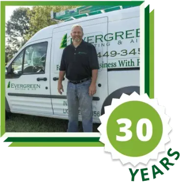 A person stands in front of a white work van with an Evergreen Heating & Air logo, featuring a 30-year anniversary emblem.