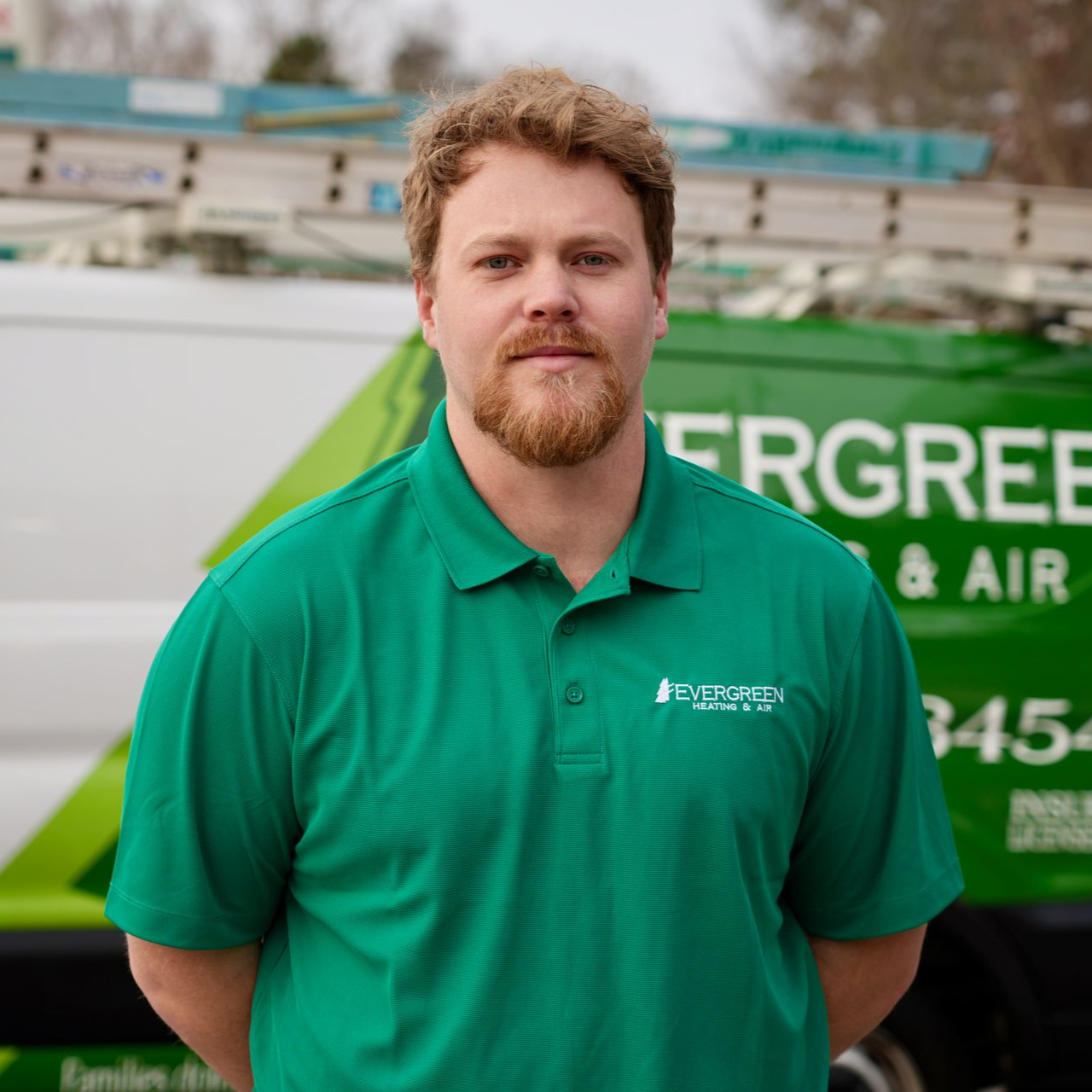 Man in green polo standing in front of an Evergreen van with company branding