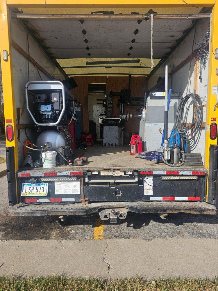 Rear view of a yellow truck bed filled with tools and equipment, including an air compressor.