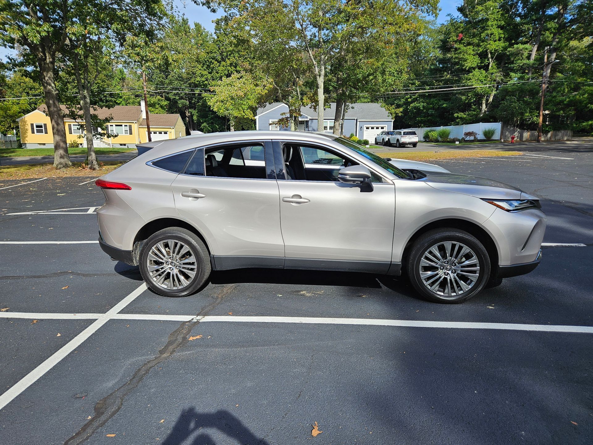 Silver SUV parked in a marked lot on a sunny day, with trees and houses in the background.
