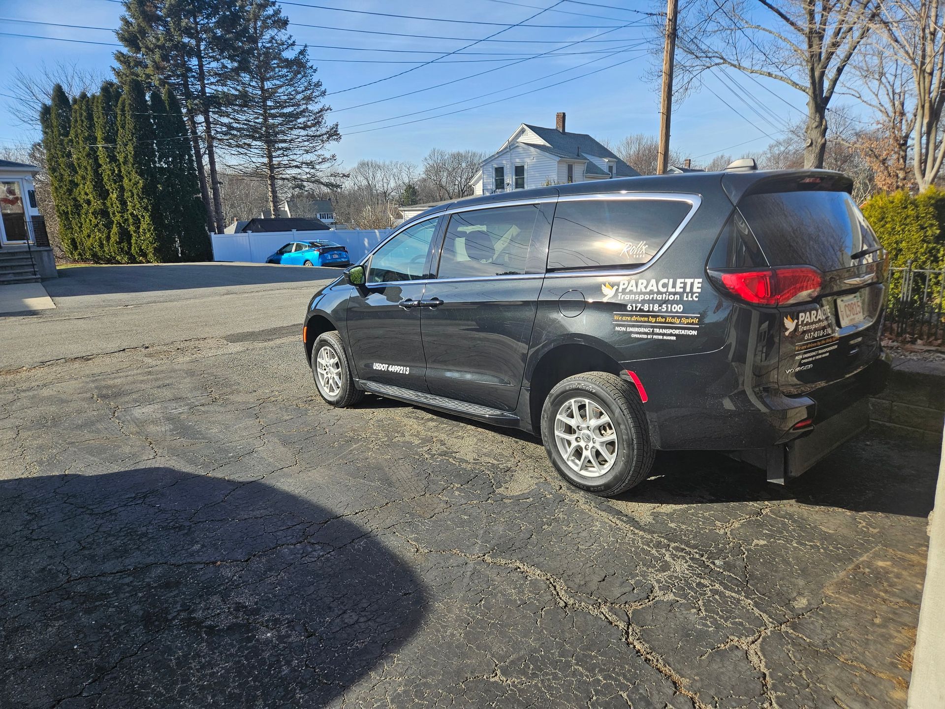 Black Chevrolet SUV parked on a gravel lot beside a road on a sunny day