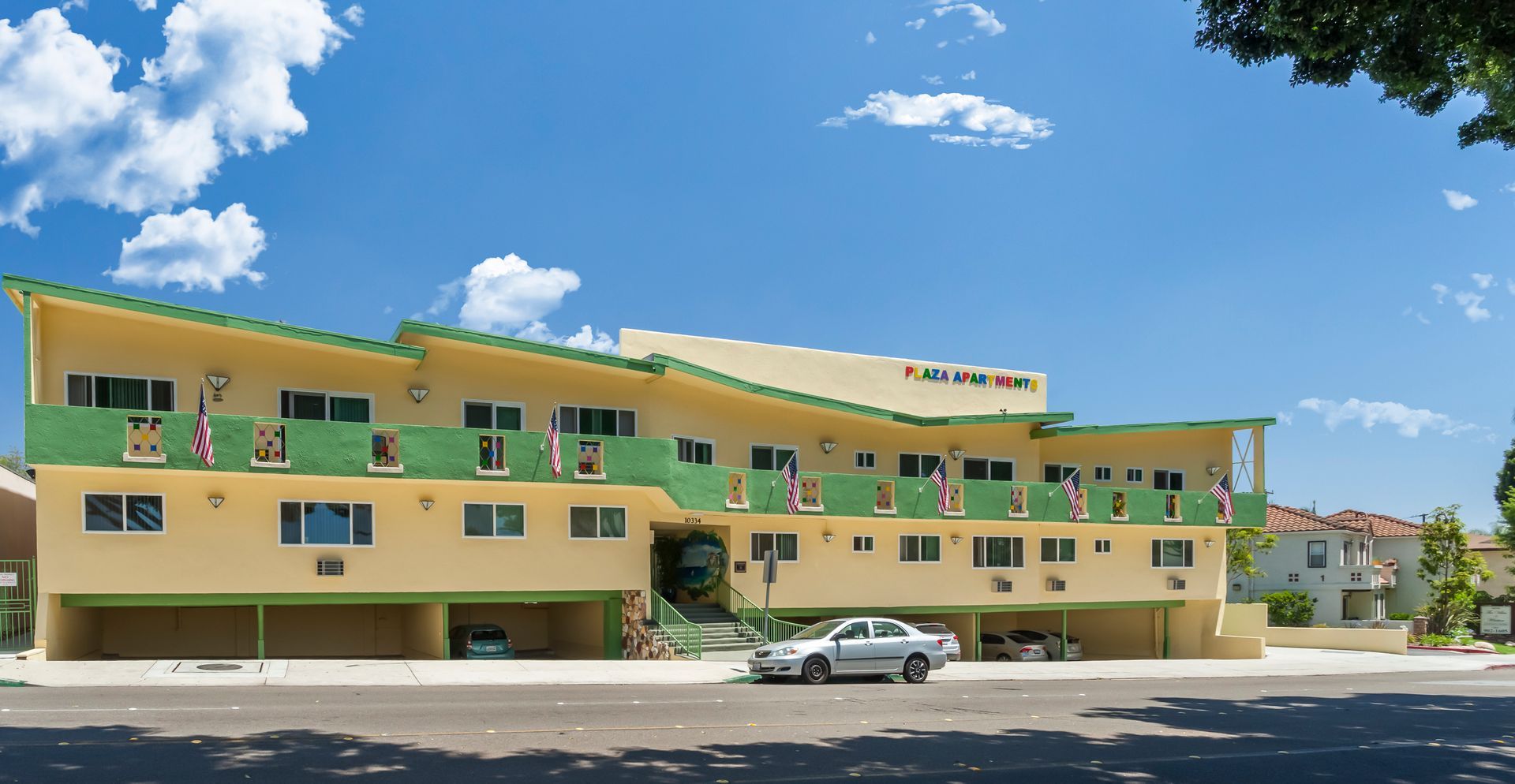 A yellow and green building with a car parked in front of it.