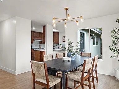 Dining room with dark table and chairs, chandelier, and a view into the kitchen.