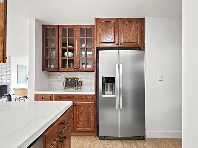 Kitchen with wooden cabinets, stainless steel refrigerator, and white countertops.