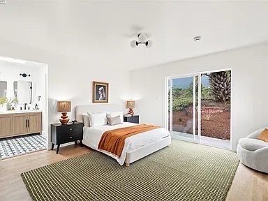 Bedroom with a bed, nightstands, rug, sliding glass door, and a bathroom entrance.
