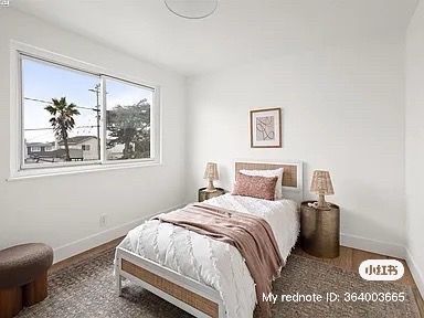 Bedroom with a bed, nightstands, rug, and window with a view of a street and palm trees.