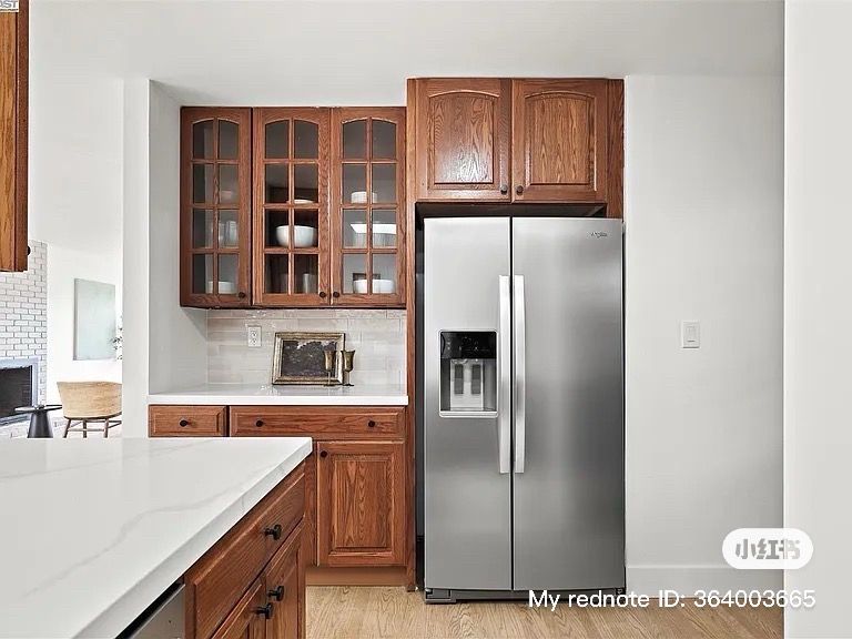 Kitchen with wood cabinets, white countertops, and stainless steel refrigerator.