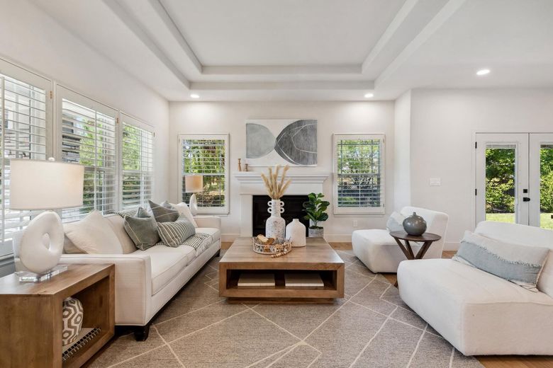 Living room with white sofa, armchairs, wood coffee table, and fireplace.