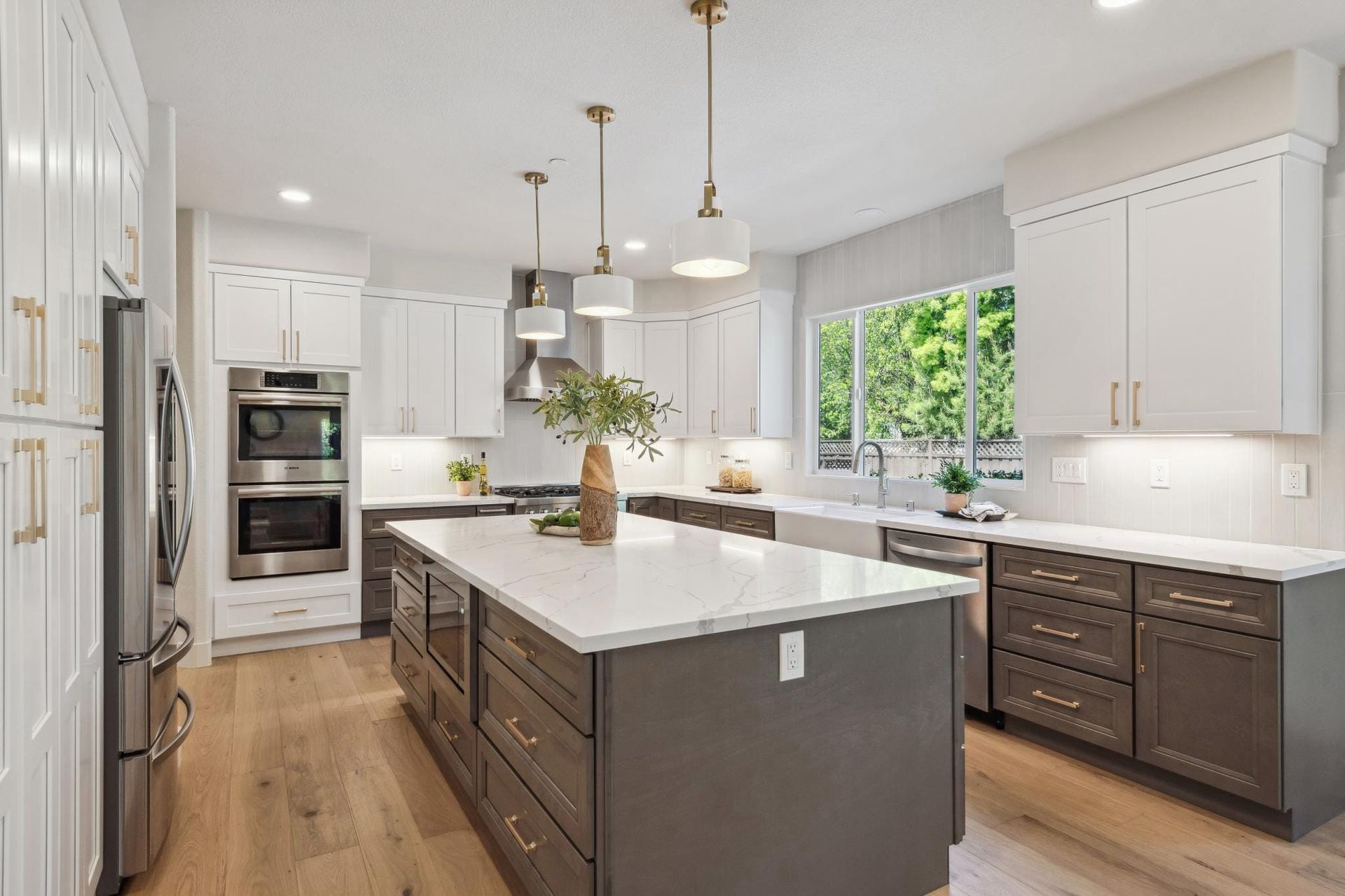 Modern kitchen with white and gray cabinets, island, and wooden floors.