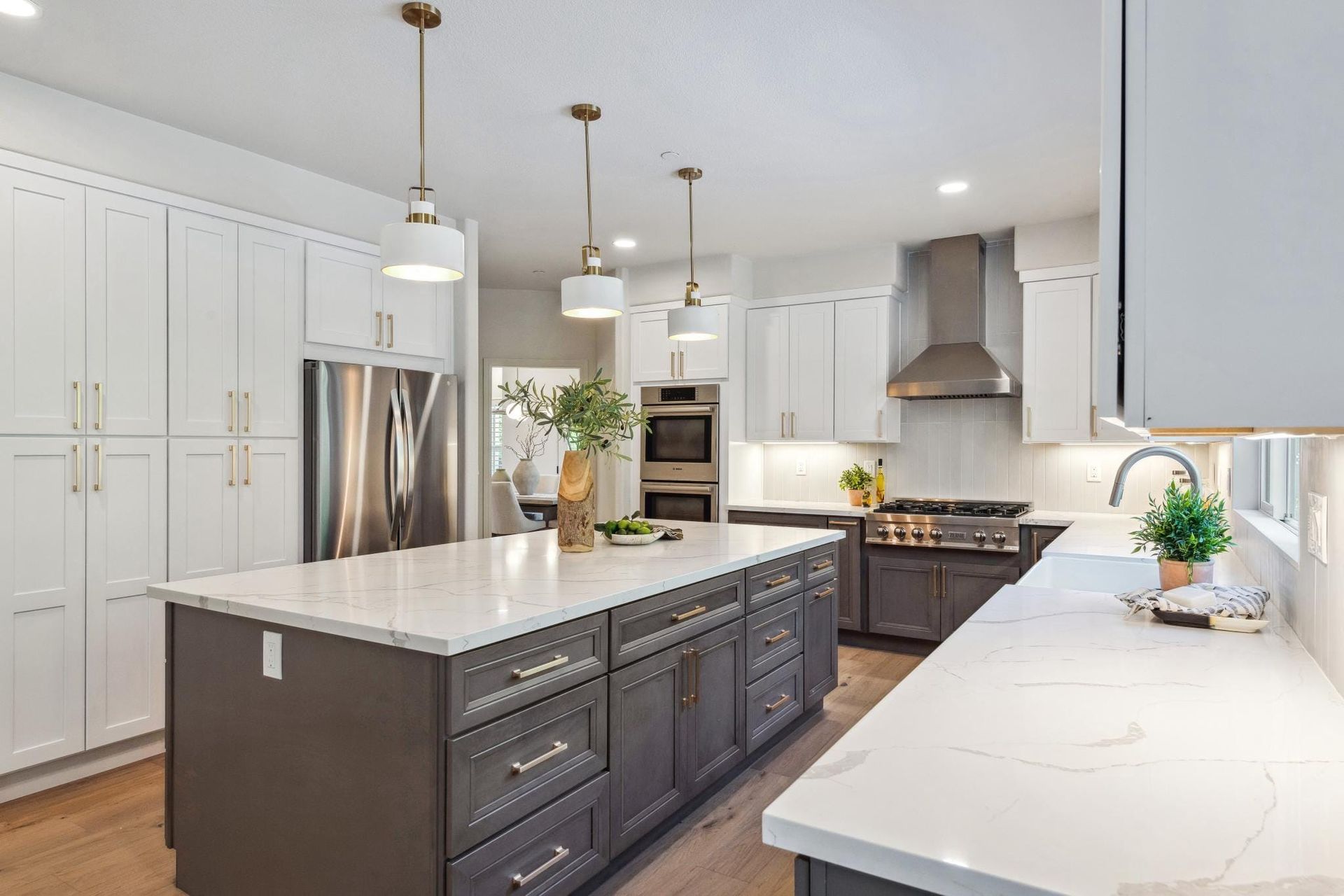 Modern kitchen with white and gray cabinets, island, stainless steel appliances, and pendant lights.
