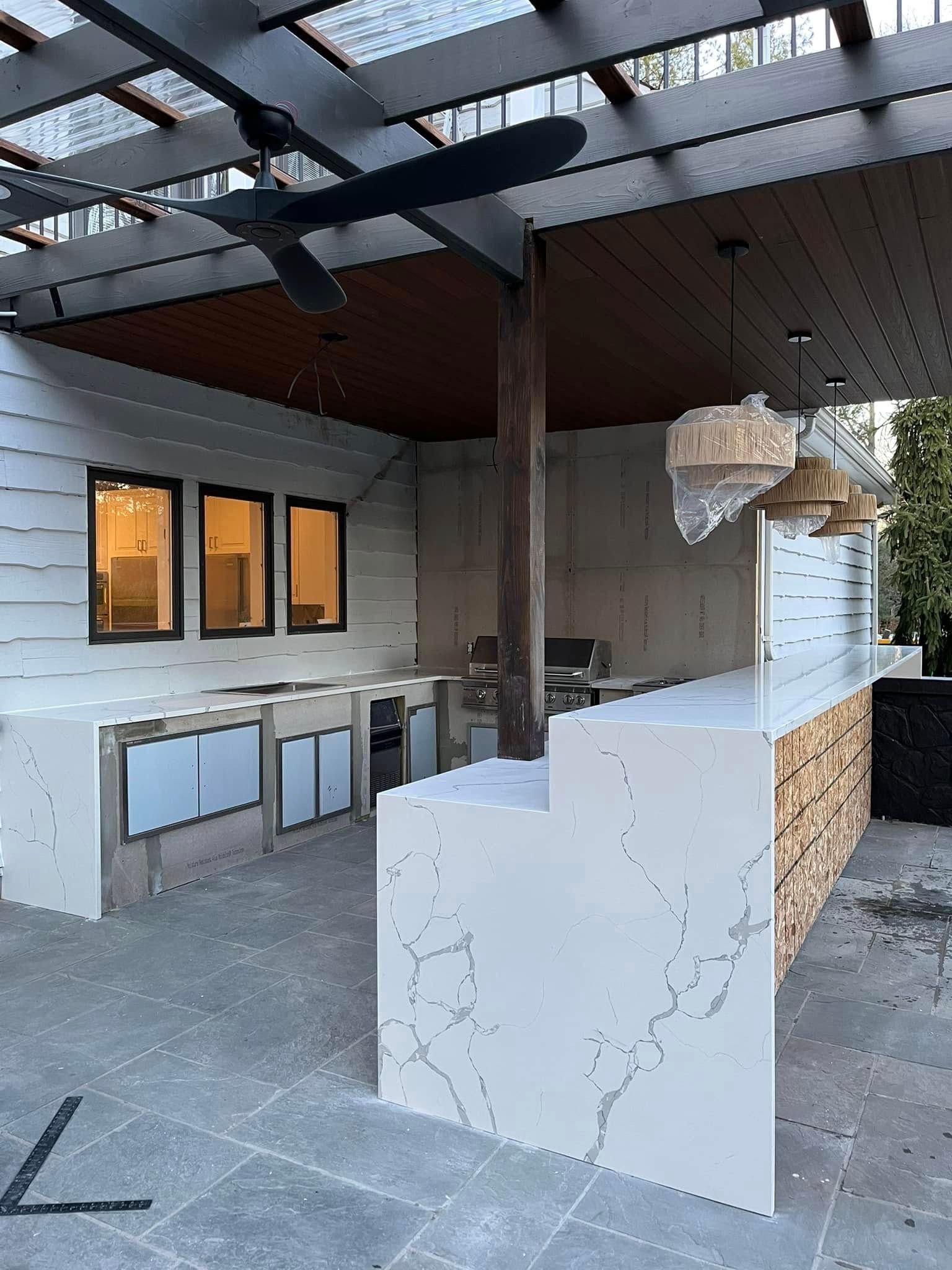 Outdoor kitchen with countertop, grill, cabinets, and a pergola.