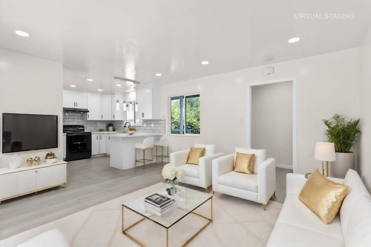 Bright, open-plan living space with a white kitchen, two white armchairs, and a white sofa.