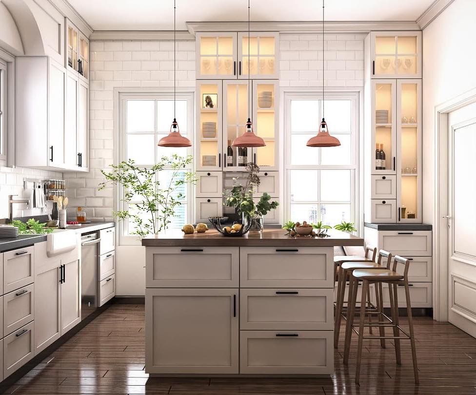 Bright, white kitchen with island, windows, copper pendant lights, wooden stools, and dark wood floor.