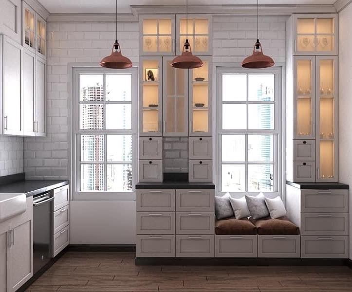 Kitchen with white cabinets, copper pendant lights, windows, and a built-in bench seat.