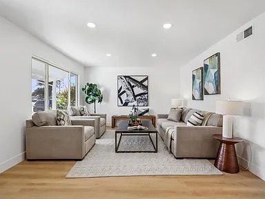 Living room with neutral furniture, artwork, and natural light.