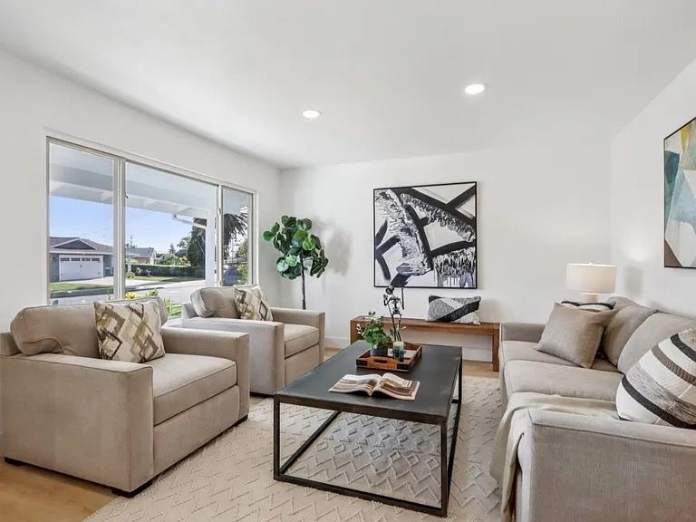 Living room with neutral furniture, large windows, and modern art.