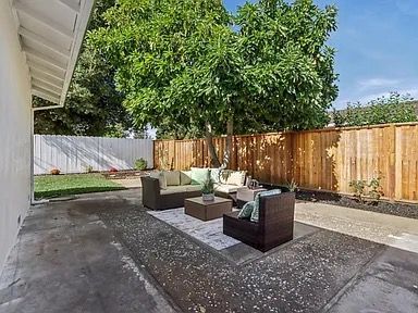 Patio with outdoor furniture, trees, and wooden fence. Concrete patio with seating arrangement and greenery.