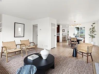 Living room with woven chairs, a black coffee table, and open to a dining area.