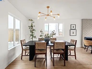 Dining room with a black table, woven chairs, and gold chandelier.