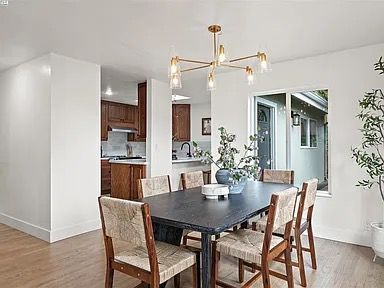 Dining room with dark table, eight chairs, gold chandelier, and view into the kitchen.