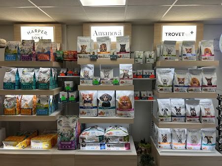 Scaffali per articoli per animali domestici con sacchi di cibo e snack per animali, contrassegnati da cartelli di diverse marche.