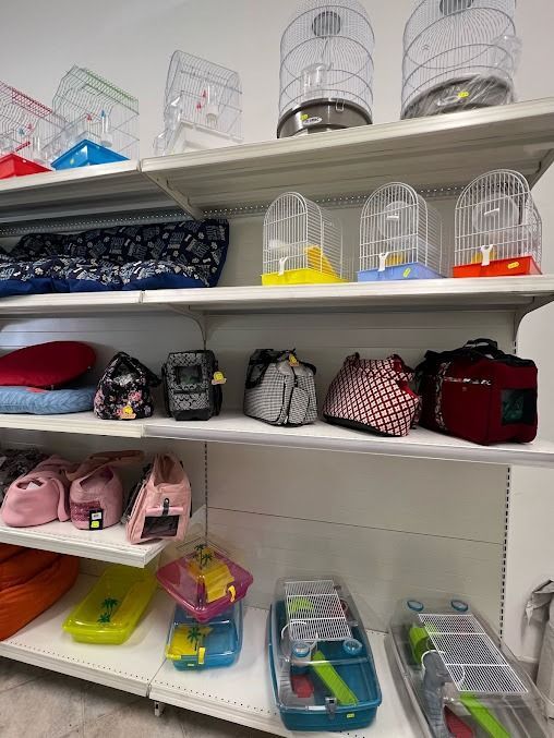 Collezione di trasportini, gabbie e accessori per animali domestici disposti su scaffali in una corsia di un negozio.